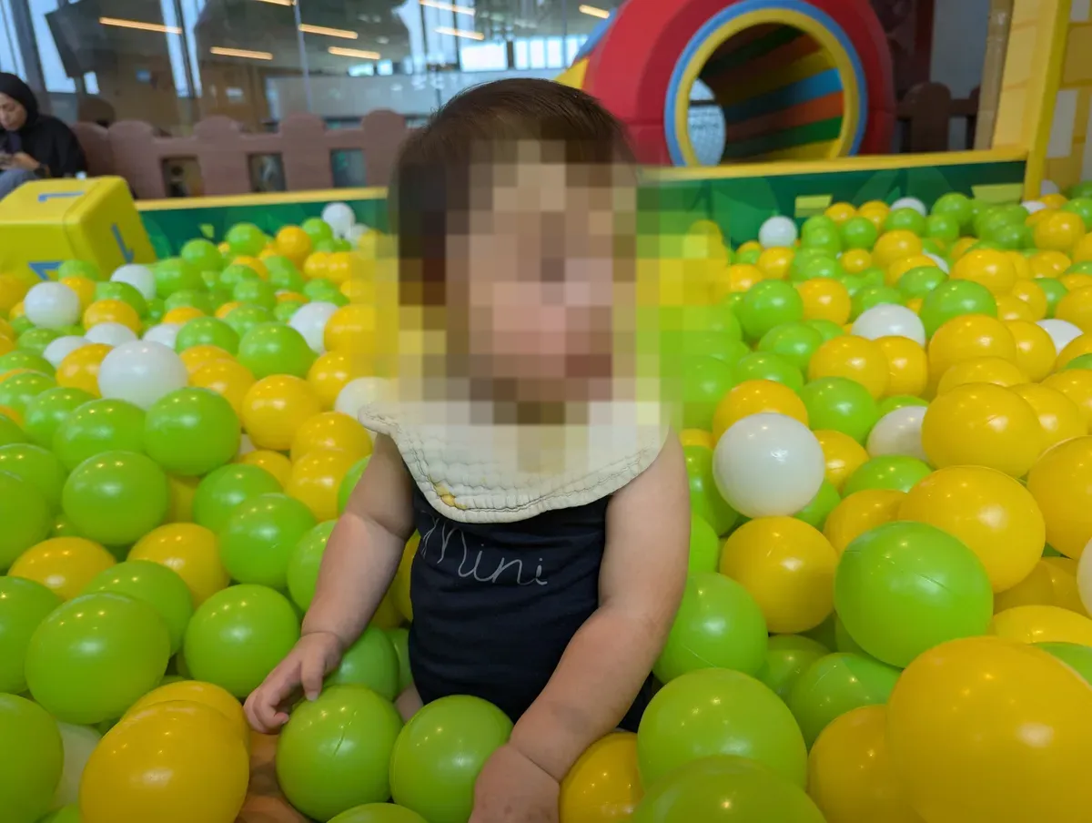A baby sitting in the green-and-yellow ball pit at Jolly Jungle, Our Tampines Hub.